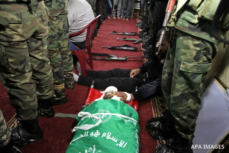 Palestinian members of the Ezzedine al-Qassam Brigades, the armed wing of the Hamas movement pray over the body of their comrade Marwan Maarouf, 27, during his funeral in Khan Yunis in the southern Gaza Strip, on Februar...