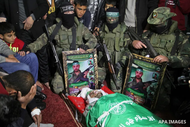 Palestinian members of the Ezzedine al-Qassam Brigades, the armed wing of the Hamas movement pray over the body of their comrade Marwan Maarouf, 27, during his funeral in Khan Yunis in the southern Gaza Strip, on Februar...