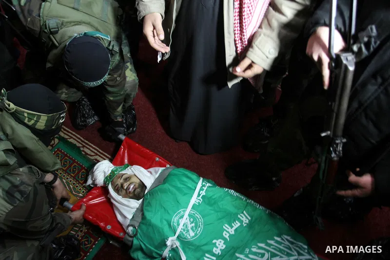 Palestinian members of the Ezzedine al-Qassam Brigades, the armed wing of the Hamas movement pray over the body of their comrade Marwan Maarouf, 27, during his funeral in Khan Yunis in the southern Gaza Strip, on Februar...