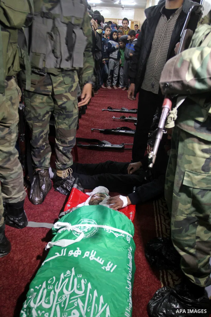 Palestinian members of the Ezzedine al-Qassam Brigades, the armed wing of the Hamas movement pray over the body of their comrade Marwan Maarouf, 27, during his funeral in Khan Yunis in the southern Gaza Strip, on Februar...