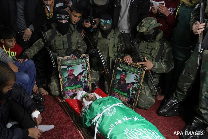 Palestinian members of the Ezzedine al-Qassam Brigades, the armed wing of the Hamas movement pray over the body of their comrade Marwan Maarouf, 27, during his funeral in Khan Yunis in the southern Gaza Strip, on Februar...