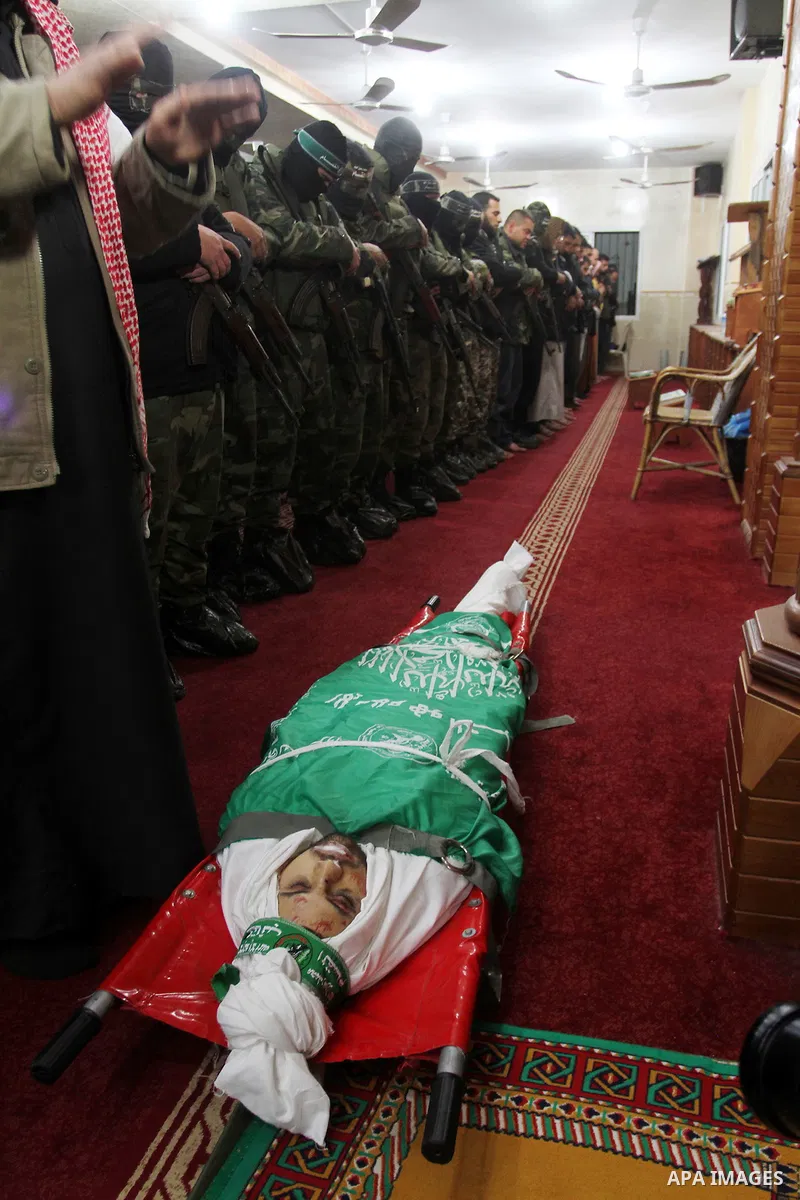 Palestinian members of the Ezzedine al-Qassam Brigades, the armed wing of the Hamas movement pray over the body of their comrade Marwan Maarouf, 27, during his funeral in Khan Yunis in the southern Gaza Strip, on Februar...