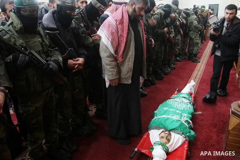 Palestinian members of the Ezzedine al-Qassam Brigades, the armed wing of the Hamas movement pray over the body of their comrade Marwan Maarouf, 27, during his funeral in Khan Yunis in the southern Gaza Strip, on Februar...