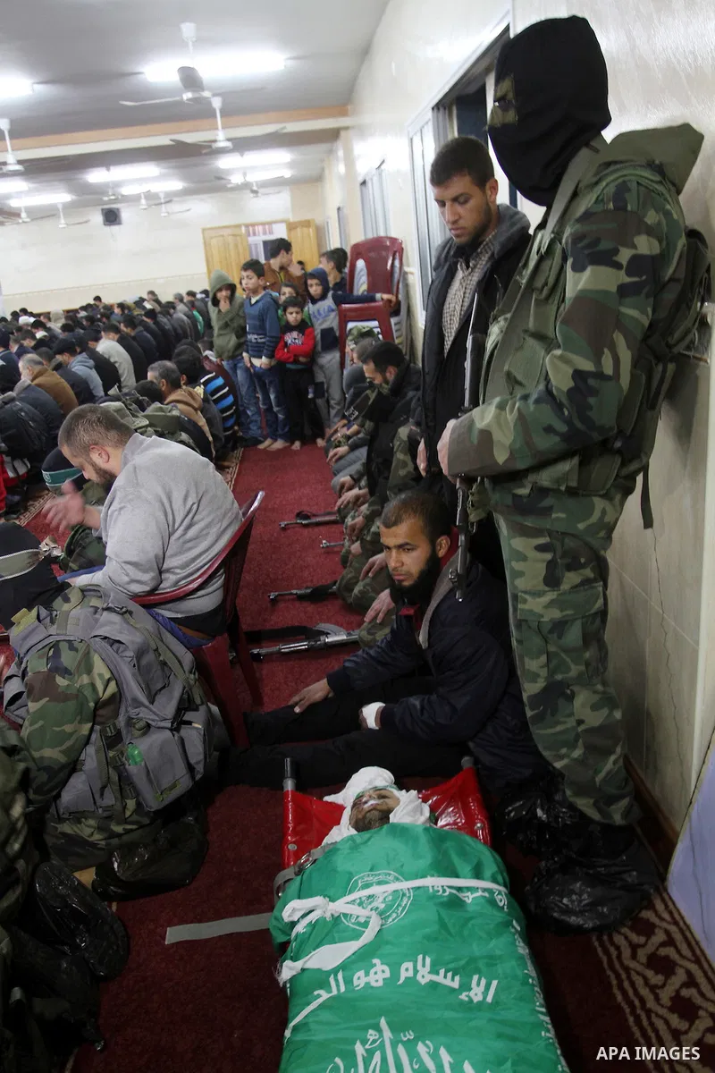 Palestinian members of the Ezzedine al-Qassam Brigades, the armed wing of the Hamas movement pray over the body of their comrade Marwan Maarouf, 27, during his funeral in Khan Yunis in the southern Gaza Strip, on Februar...