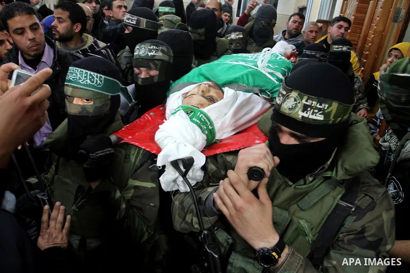 Palestinian members of the Ezzedine al-Qassam Brigades, the armed wing of the Hamas movement carry the body of their comrade Marwan Maarouf, 27, during his funeral in Khan Yunis in the southern Gaza Strip, on February 9,...