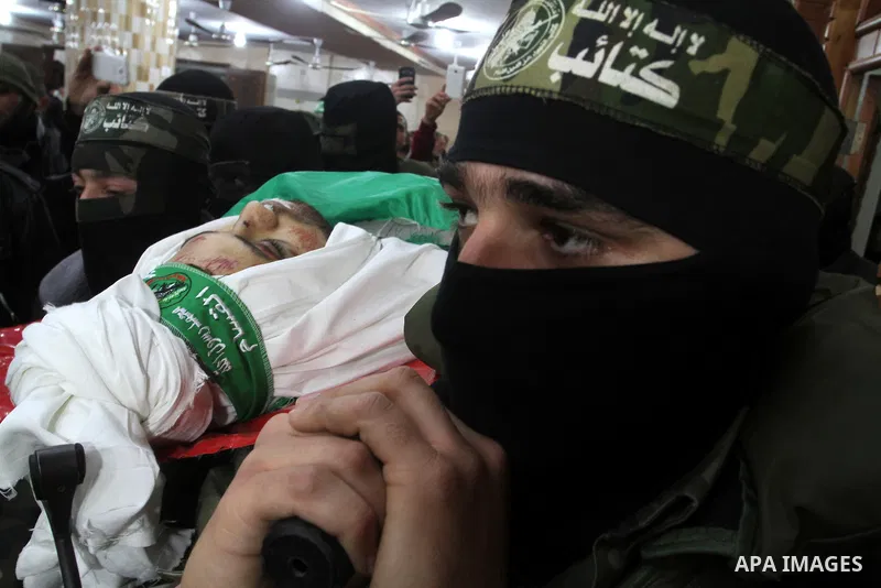 Palestinian members of the Ezzedine al-Qassam Brigades, the armed wing of the Hamas movement carry the body of their comrade Marwan Maarouf, 27, during his funeral in Khan Yunis in the southern Gaza Strip, on February 9,...