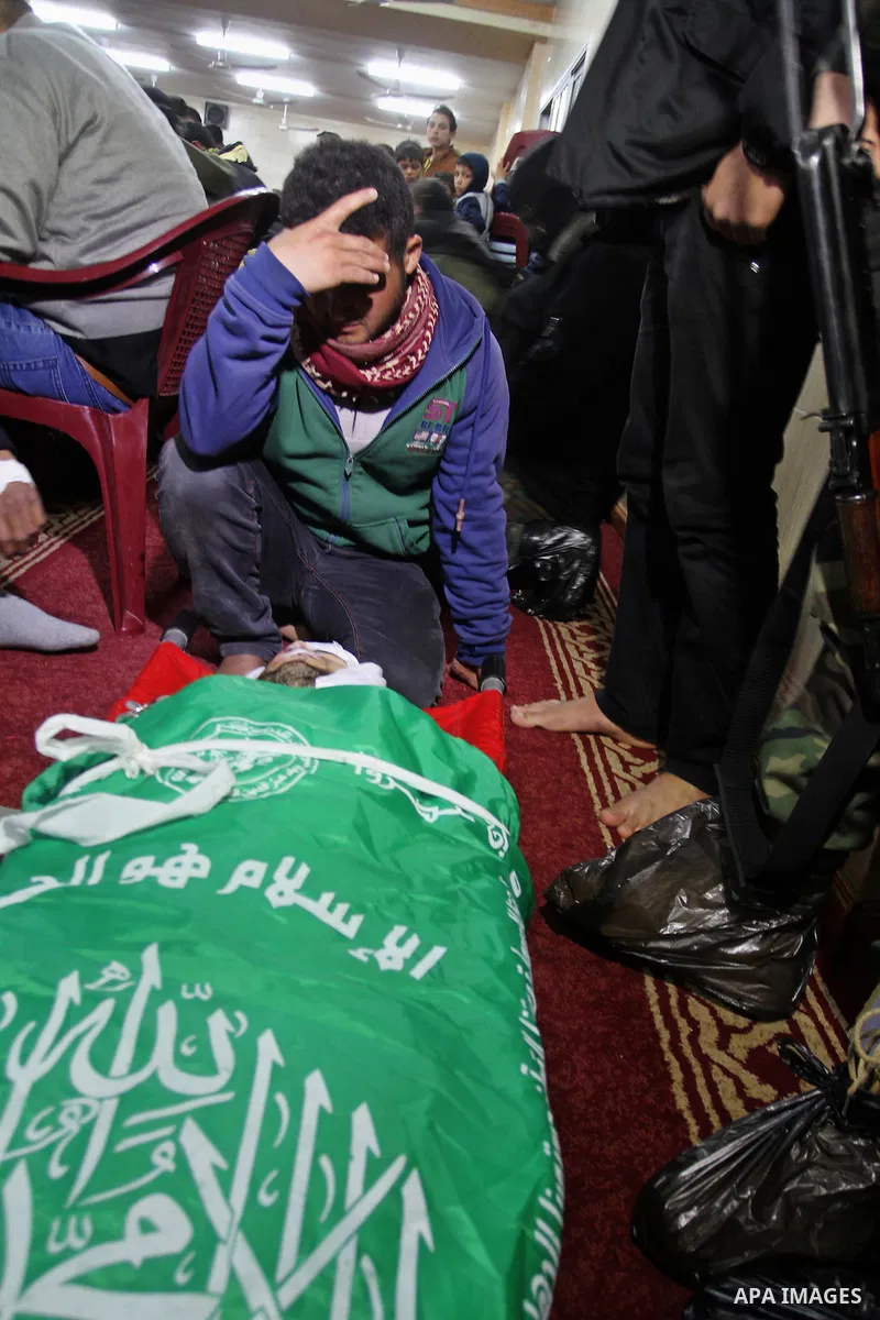 Palestinian members of the Ezzedine al-Qassam Brigades, the armed wing of the Hamas movement pray over the body of their comrade Marwan Maarouf, 27, during his funeral in Khan Yunis in the southern Gaza Strip, on Februar...