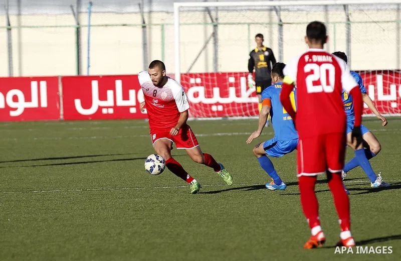 Ahly Al-Khalil football club's players (in red) and FC Khujand club's players compete during the football match crucial AFC Champions League Playoff phase at Dura Stadium in the West Bank city of Hebron on Feb. 09, 2016....