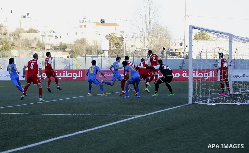 Ahly Al-Khalil football club's players (in red) and FC Khujand club's players compete during the football match crucial AFC Champions League Playoff phase at Dura Stadium in the West Bank city of Hebron on Feb. 09, 2016....