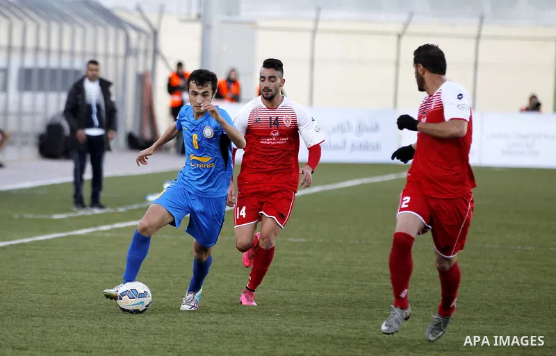 Ahly Al-Khalil football club's players (in red) and FC Khujand club's players compete during the football match crucial AFC Champions League Playoff phase at Dura Stadium in the West Bank city of Hebron on Feb. 09, 2016....
