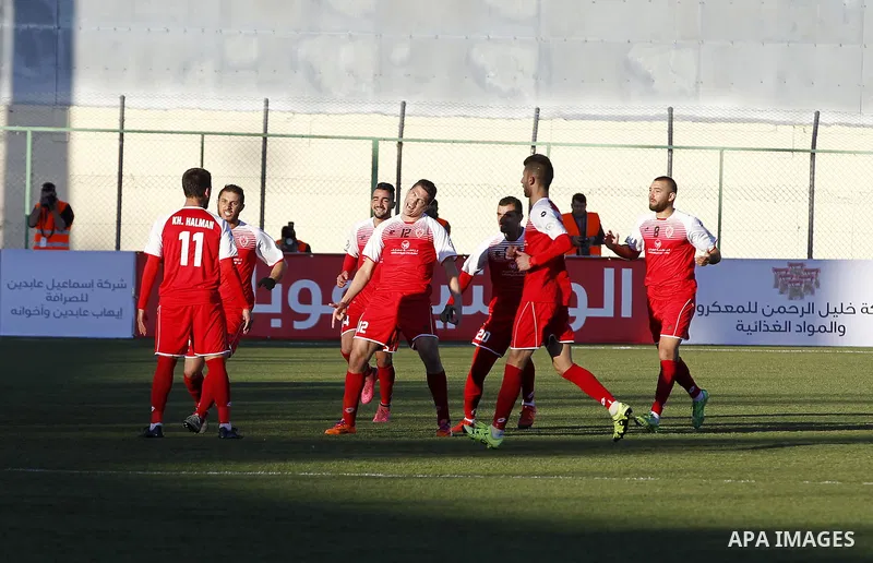 Ahly Al-Khalil football club's players (in red) and FC Khujand club's players compete during the football match crucial AFC Champions League Playoff phase at Dura Stadium in the West Bank city of Hebron on Feb. 09, 2016....