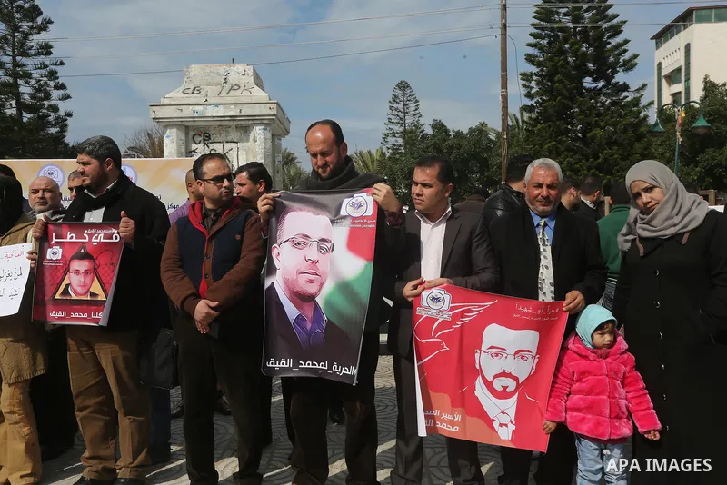 Palestinians hold posters during a protest in support of hunger striking Palestinian journalist Mohammed al-Qiq, in in Gaza city on February 10, 2016. The 33-year-old television reporter will keep up his 10-week hunger s...