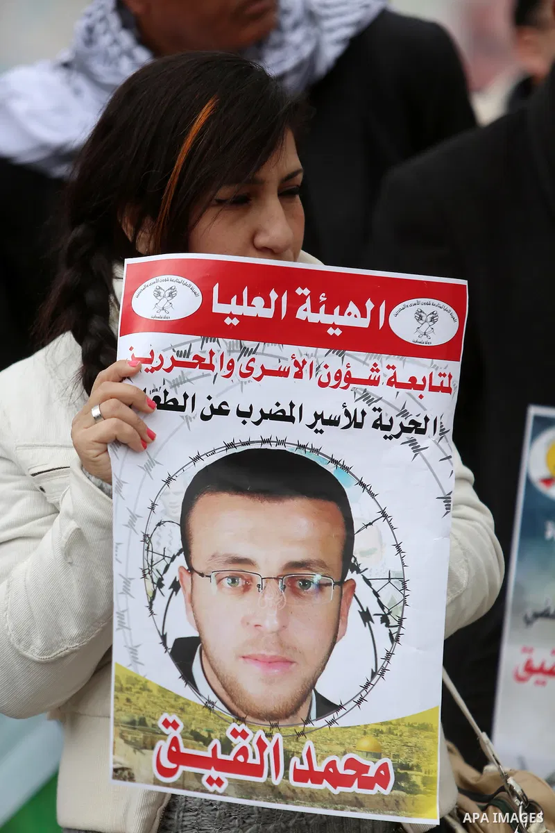 Palestinians hold posters during a protest in support of hunger striking Palestinian journalist Mohammed al-Qiq, in the West Bank city of Ramallah on February 11, 2016. The 33-year-old television reporter will keep up hi...