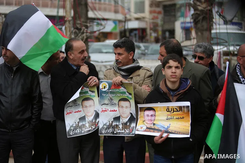 Palestinians hold posters during a protest in support of hunger striking Palestinian journalist Mohammed al-Qiq, in the West Bank city of Ramallah on February 11, 2016. The 33-year-old television reporter will keep up hi...