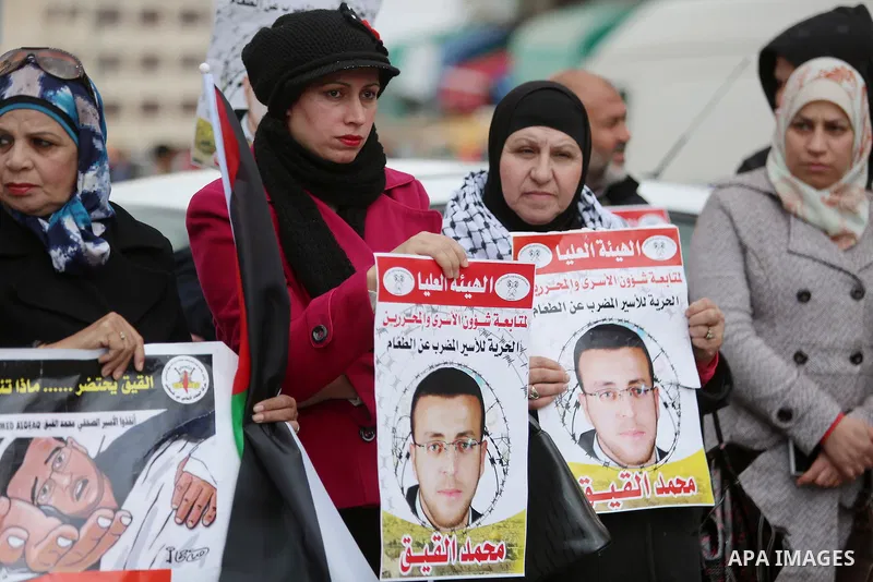 Palestinians hold posters during a protest in support of hunger striking Palestinian journalist Mohammed al-Qiq, in the West Bank city of Ramallah on February 11, 2016. The 33-year-old television reporter will keep up hi...