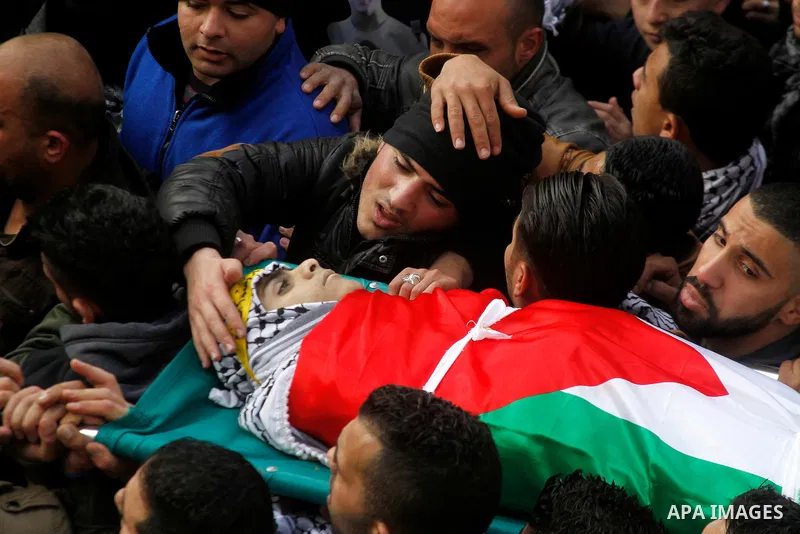 Palestinian mourners carry the body of Omar Jawabra, who was killed by Israeli fire during clashes near Hebron the day before, during his funeral at al-Aroub Palestinian refugee camp, north the West Bank city of Hebron o...