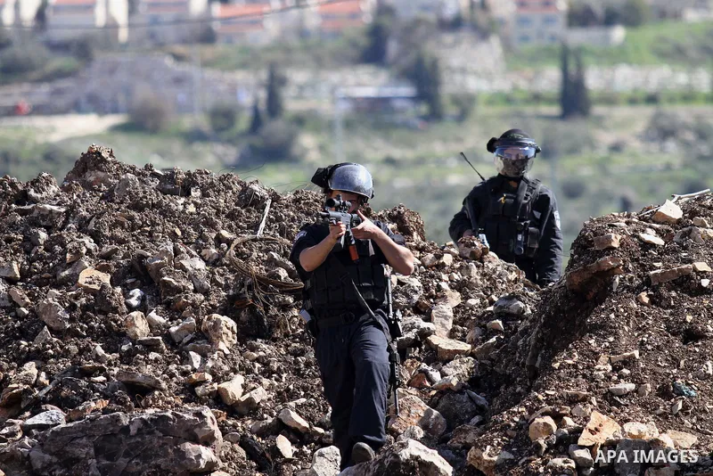 A member of Israeli security forces aims his weapon at Palestinian protesters during clashes following a protest against the expropriation of Palestinian land by Israel in the West Bank village of Kafr Qaddum, near the n...