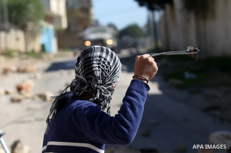 A Palestinian protester uses a slingshot to hurl stones toward Israeli security forces during clashes following a protest against the expropriation of Palestinian land by Israel in the West Bank village of Kafr Qaddum, n...