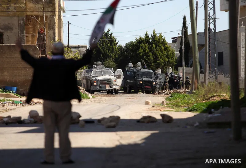 A Palestinian protester holds a national flag during clashes with Israeli security forces following a protest against the expropriation of Palestinian land by Israel in the West Bank village of Kafr Qaddum, near the nort...