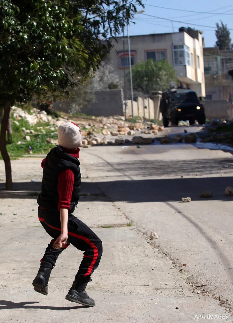 A Palestinian protester throws stones toward Israeli security forces during clashes following a protest against the expropriation of Palestinian land by Israel in the West Bank village of Kafr Qaddum, near the northern c...