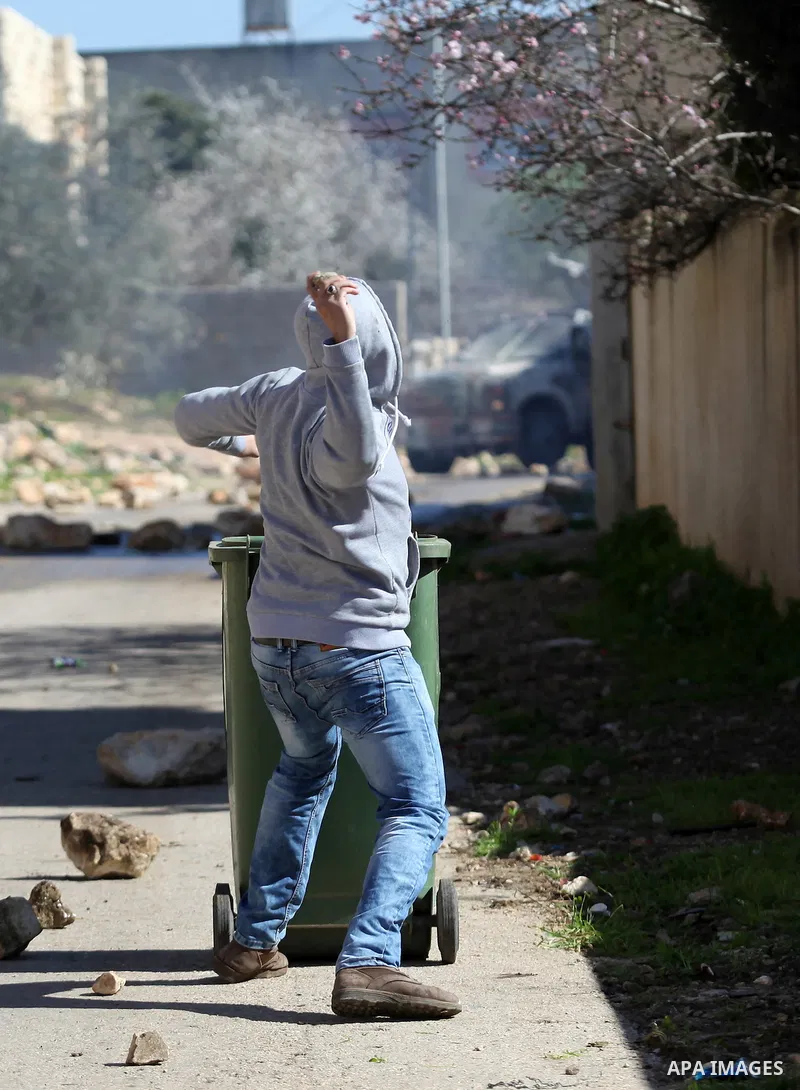A Palestinian protester throws stones toward Israeli security forces during clashes following a protest against the expropriation of Palestinian land by Israel in the West Bank village of Kafr Qaddum, near the northern c...
