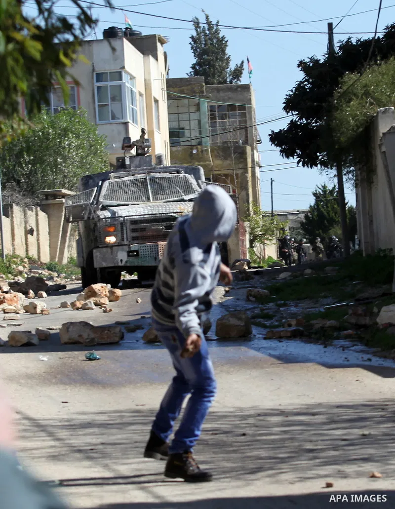 A Palestinian protester throws stones toward Israeli security forces during clashes following a protest against the expropriation of Palestinian land by Israel in the West Bank village of Kafr Qaddum, near the northern c...