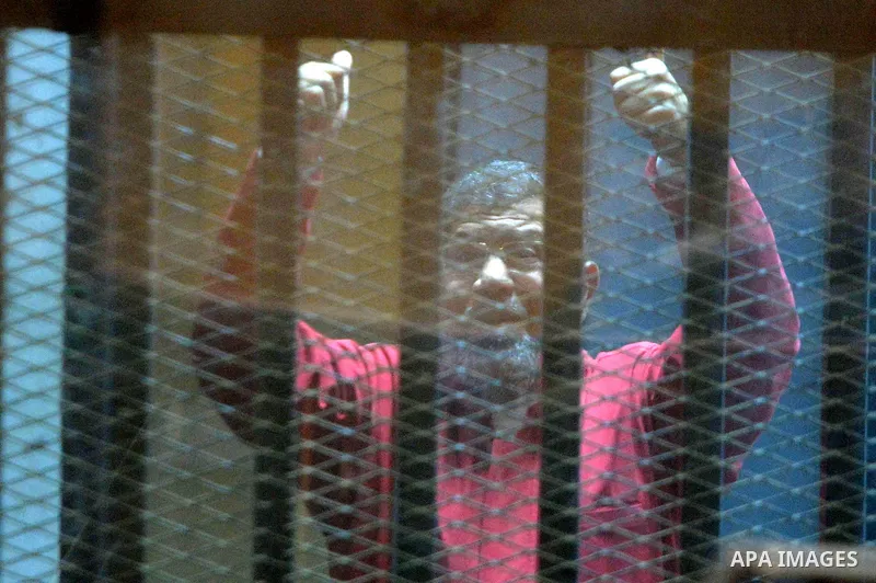 Ousted Egyptian president Mohammed Morsi sits behind bars during his trail as part of the so-called 'Qatar espionage' case, in a court in Cairo on Feb. 13, 2016. The defendants are accused of 'leaking important national...