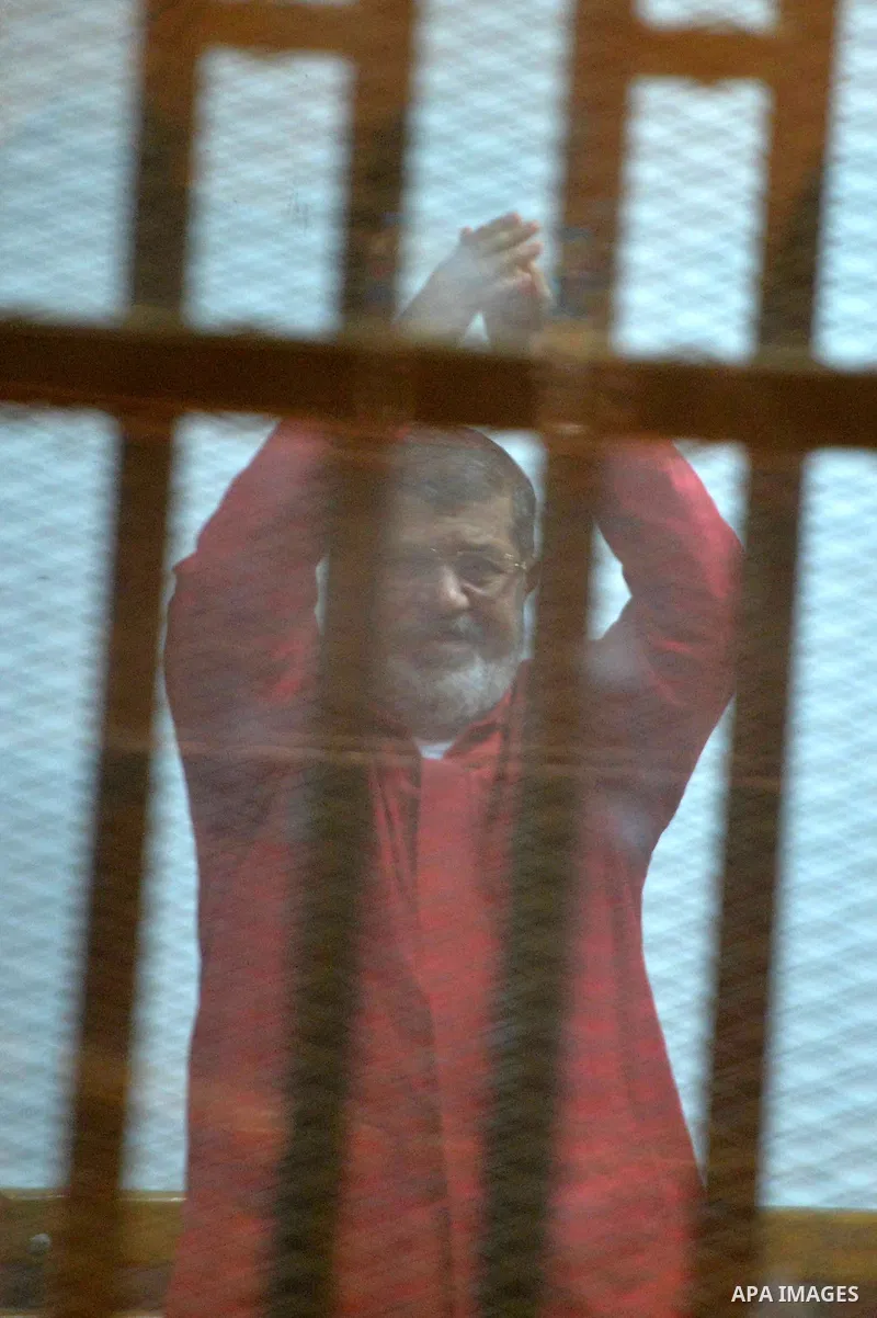 Ousted Egyptian president Mohammed Morsi sits behind bars during his trail as part of the so-called 'Qatar espionage' case, in a court in Cairo on Feb. 13, 2016. The defendants are accused of 'leaking important national...