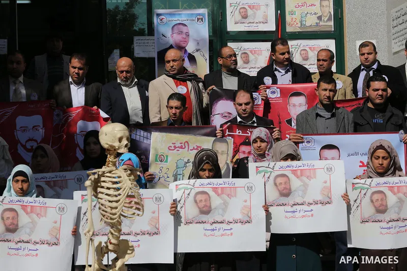 Palestinians hold posters during a protest in support of hunger striking Palestinian journalist Mohammed al-Qiq, in Gaza city on February 14, 2016. The 33-year-old television reporter will keep up his 10-week hunger stri...