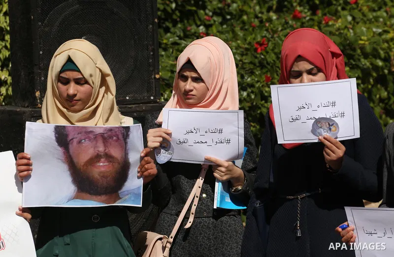 Palestinians hold posters during a protest in support of hunger striking Palestinian journalist Mohammed al-Qiq, in Gaza city on February 14, 2016. The 33-year-old television reporter will keep up his 10-week hunger stri...