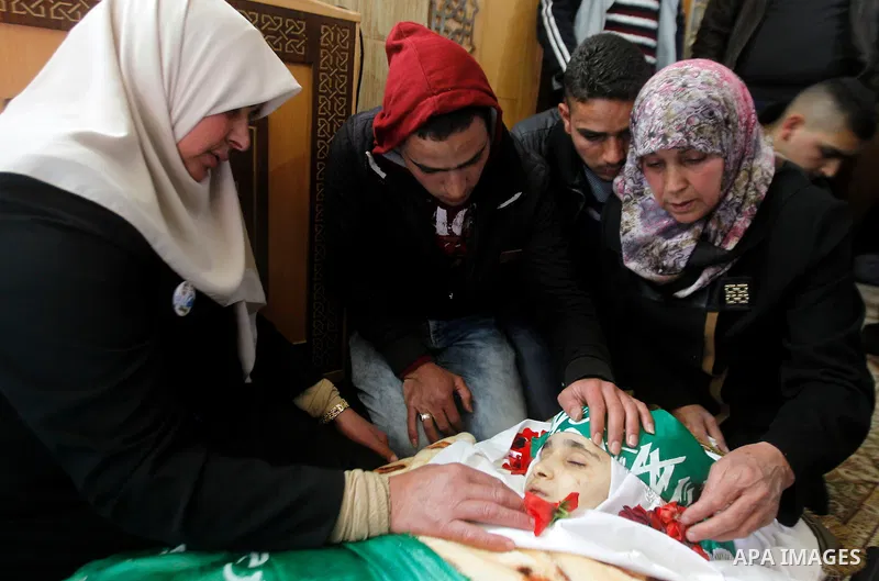 The relatives of Palestinian Kalzar al-Uweiwi, a Palestinian teenager who was killed a day earlier following a reported stabbing attack, mourn over her body ahead of her funeral, in the Israeli occupied West Bank city of...