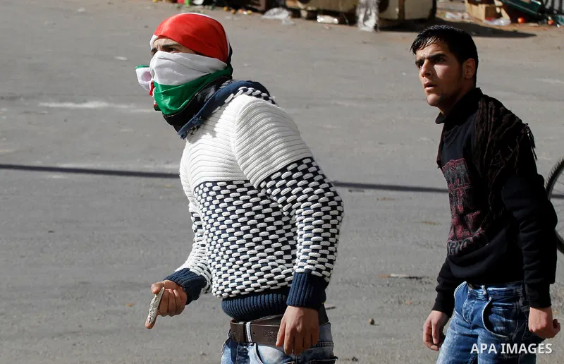A Palestinian protester hurls stones toward Israeli security forces during clashes following the funeral of Kalzar al-Uweiwi, a Palestinian teenager who was killed a day earlier following a reported stabbing attack, in t...