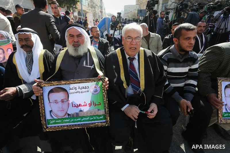 Palestinians hold posters during a protest in support of hunger striking Palestinian journalist Mohammed al-Qiq, in front of the Red cross office, Gaza city on February 14, 2016. The 33-year-old television reporter will...
