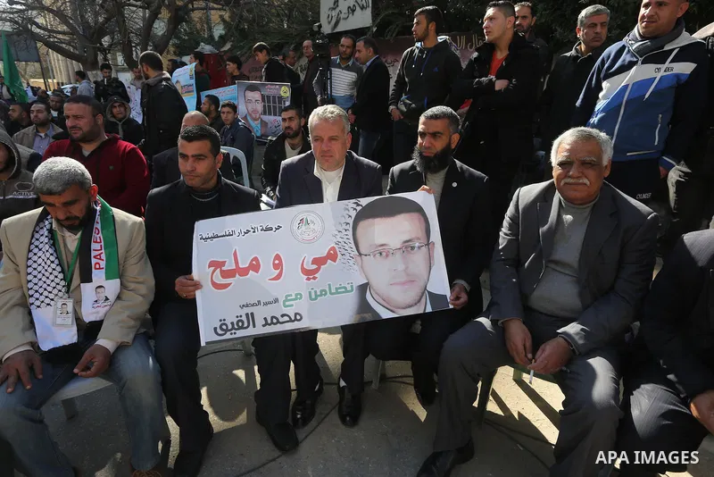 Palestinians hold posters during a protest in support of hunger striking Palestinian journalist Mohammed al-Qiq, in front of the Red cross office, Gaza city on February 14, 2016. The 33-year-old television reporter will...