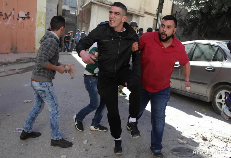 A Palestinian man, reported to be injured in the foot, is evacuated on February 15, 2016 on a street at the Amari refugee camp, near the West Bank city of Ramallah, during clashes that erupted after Israeli soldiers ente...