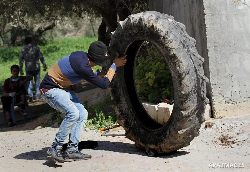 A Palestinian protester uses a tire to take cover during clashes with Israeli security forces in the village of Araka, West of Jenin in the Israeli occupied West Bank on February 15, 2016. Photo by Nedal Eshtayah