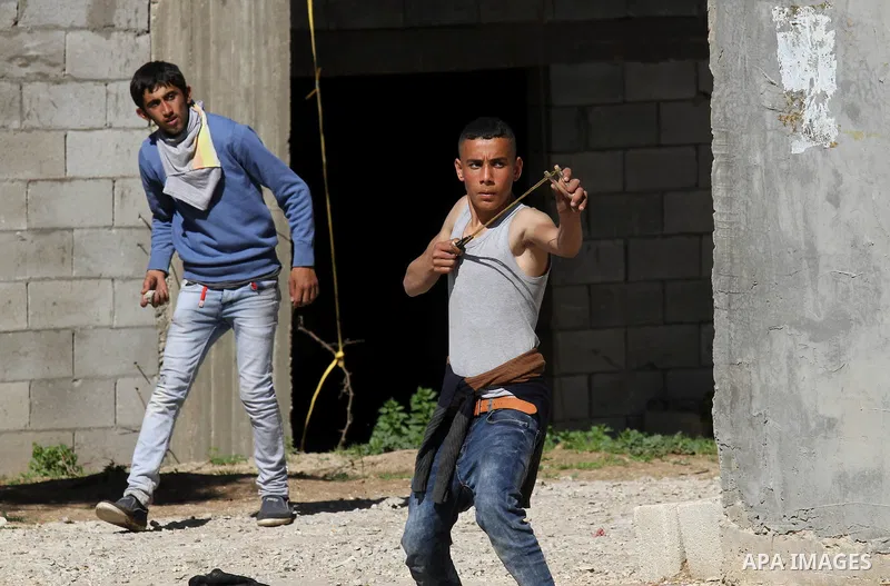 A Palestinian protester uses a slingshot to hurl stones toward Israeli security forces during clashes in the village of Araka, West of Jenin in the Israeli occupied West Bank on February 15, 2016. Photo by Nedal Eshtayah