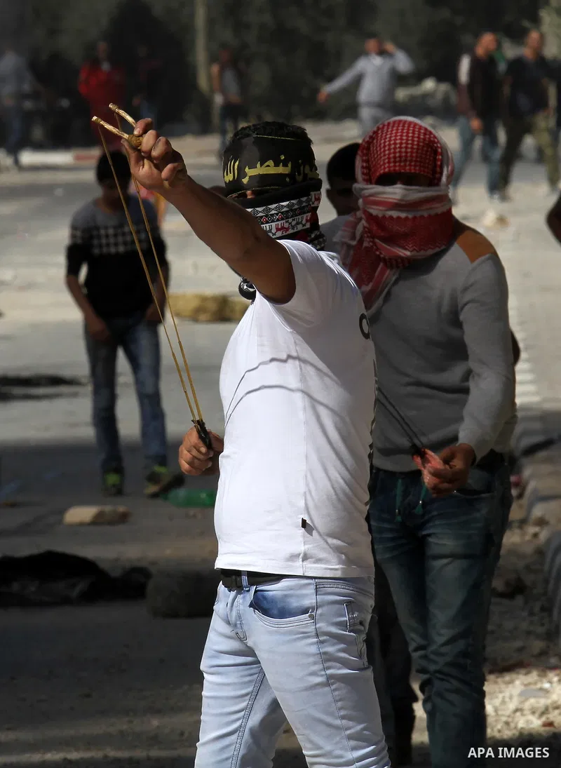 A Palestinian protester uses a slingshot to hurl stones toward Israeli security forces during clashes in the village of Araka, West of Jenin in the Israeli occupied West Bank on February 15, 2016. Photo by Nedal Eshtayah