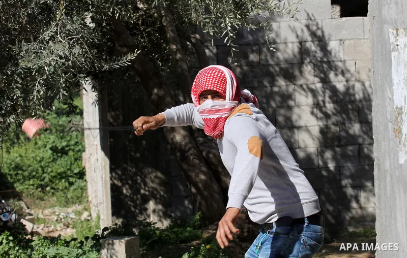 A Palestinian protester uses a slingshot to hurl stones toward Israeli security forces during clashes in the village of Araka, West of Jenin in the Israeli occupied West Bank on February 15, 2016. Photo by Nedal Eshtayah