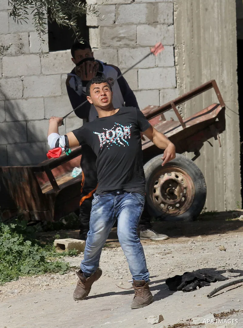A Palestinian protester uses a slingshot to hurl stones toward Israeli security forces during clashes in the village of Araka, West of Jenin in the Israeli occupied West Bank on February 15, 2016. Photo by Nedal Eshtayah
