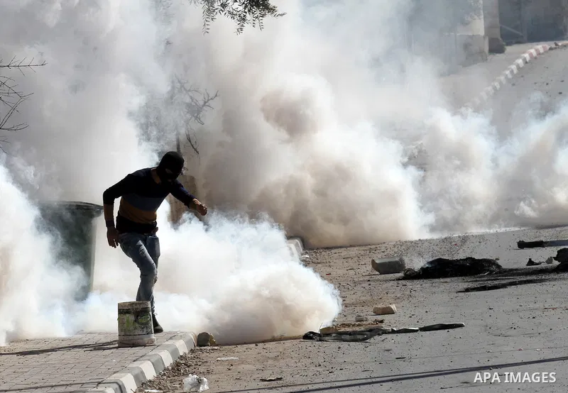 A Palestinian protester runs for cover from a tear gas canister fired by Israeli security forces during clashes in the village of Araka, West of Jenin in the Israeli occupied West Bank on February 15, 2016. Photo by Neda...