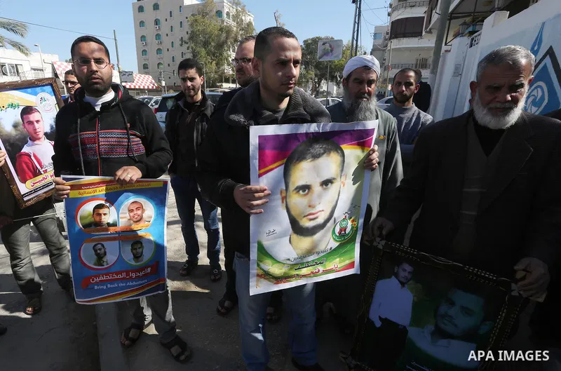 Relatives of four Palestinian men abducted by unidentified masked gunmen on August 19, hold their relatives' pictures during a protest demanding for their return, in Gaza city on February 17, 2016. Photo by Mohammed Asad