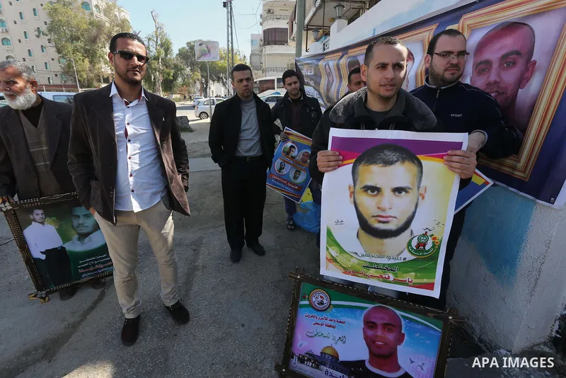 Relatives of four Palestinian men abducted by unidentified masked gunmen on August 19, hold their relatives' pictures during a protest demanding for their return, in Gaza city on February 17, 2016. Photo by Mohammed Asad