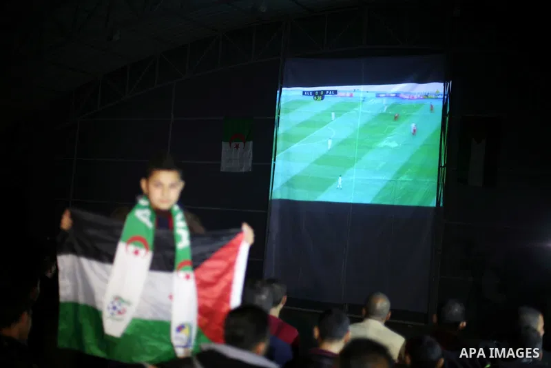 Palestinian fans watch on giant screens a friendly football match between Palestinian team and Algeria's team in Gaza city on Feb. 17, 2016. Photo by Mohammed Asad