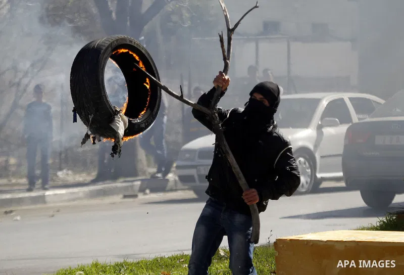 A Palestinian protester burns tires during clashes with Israeli security forces (unseen) to show solidarity with Mohammed al-Qiq a Palestinian prisoner on hunger strike, in the West bank city of Hebron on February 19, 20...