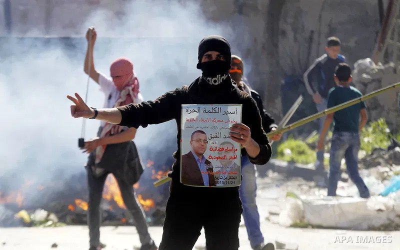 A Palestinian protester holds a poster of Mohammed al-Qiq, a Palestinian prisoner on hunger strike during clashes with Israeli security foces in the West bank city of Hebron on February 19, 2016. Photo by Wisam Hashlamou...