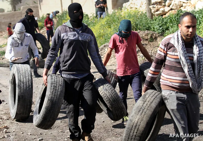 Palestinian protesters carry tires during clashes with Israeli security forces following a demonstration against the expropriation of Palestinian land by Israel on February 19, 2016 in the village of Kfar Qaddum, near Na...
