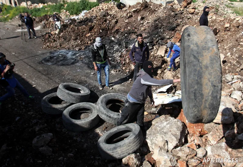 Palestinian protesters carry tires during clashes with Israeli security forces following a demonstration against the expropriation of Palestinian land by Israel on February 19, 2016 in the village of Kfar Qaddum, near Na...