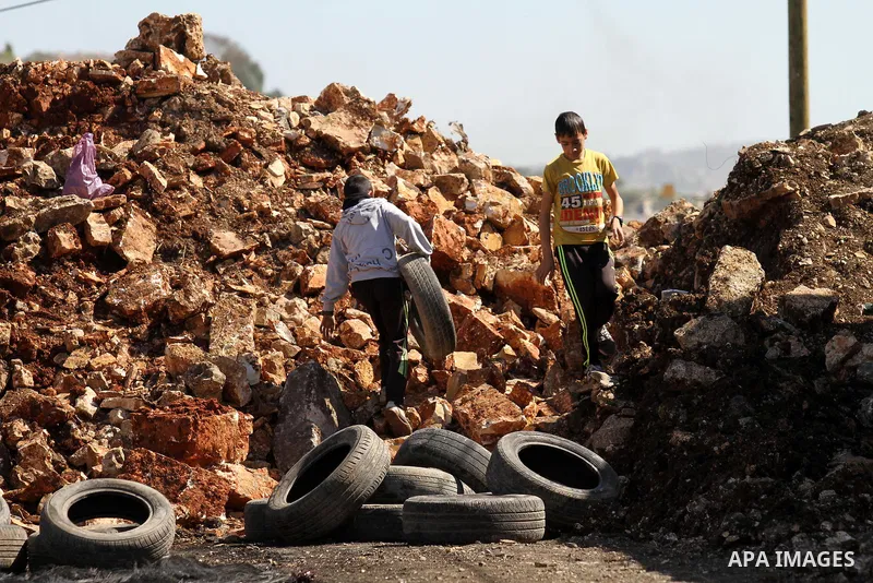 Palestinian protesters carry tires during clashes with Israeli security forces following a demonstration against the expropriation of Palestinian land by Israel on February 19, 2016 in the village of Kfar Qaddum, near Na...
