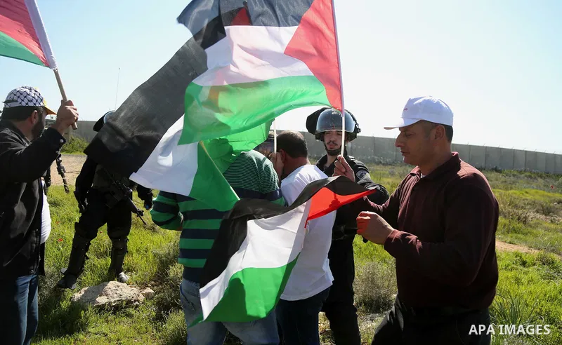 Palestinians hold national flags during clashes with Israeli security forces following a march on February 19, 2016 in the West Bank village of Bilin, near Ramallah, to mark the 11th anniversary of their uprising against...
